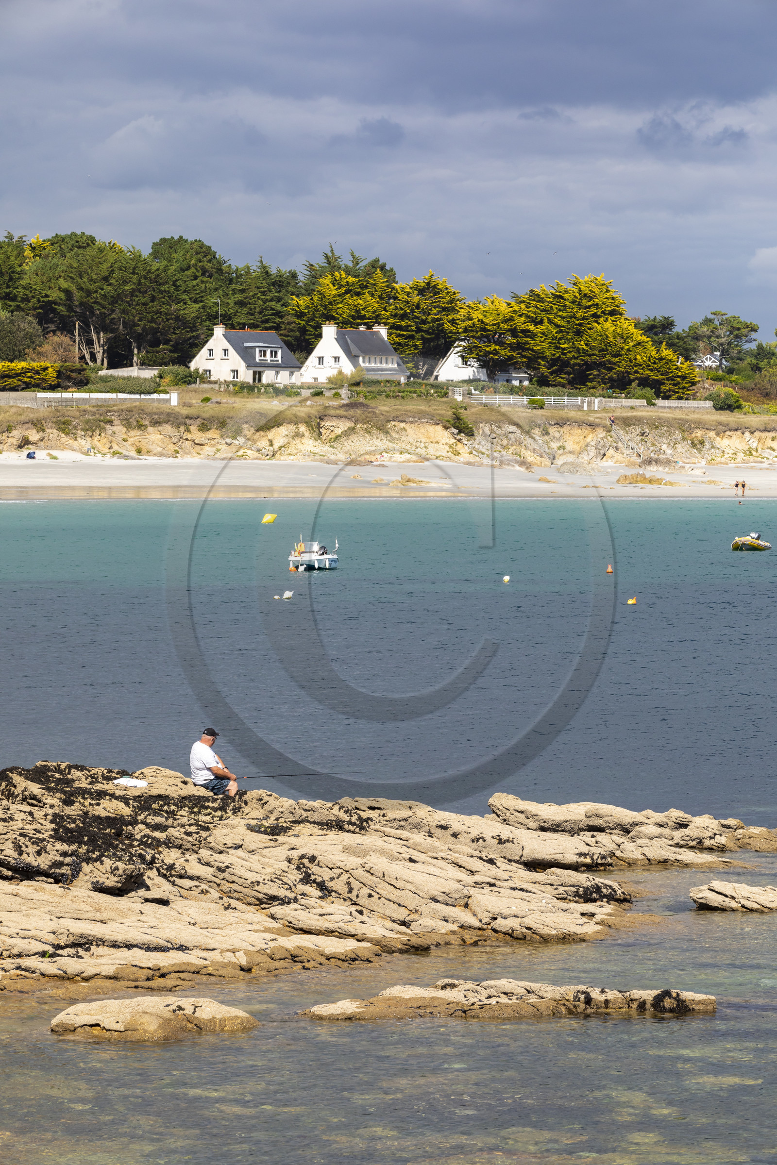 Pêcheur sur la pointe de Kerjean sur la commune de Trégunc. En arrière-plan, la plage de Kersidan
