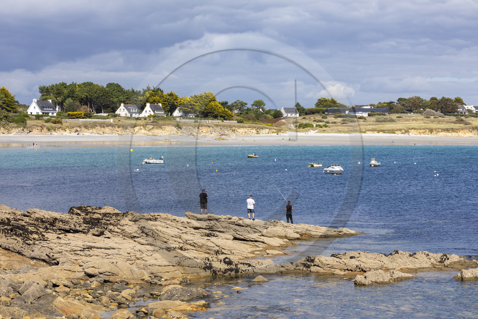 Pêcheur sur la pointe de Kerjean sur la commune de Trégunc. En arrière-plan, la plage de Kersidan